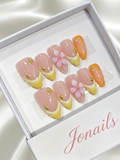 Nude pink press-on nails with yellow French tips, 3D pink cherry blossom flower and gold bee charm