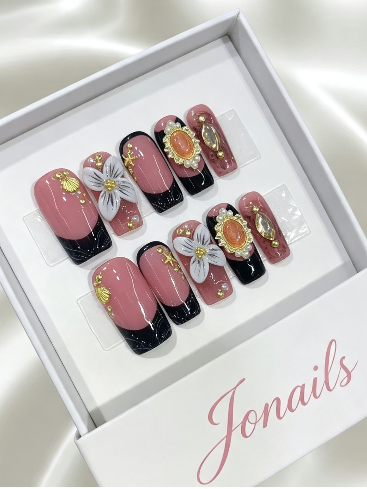 Dusty rose and black French tip press-on nails with 3D white flower, amber gemstone and pearl accents