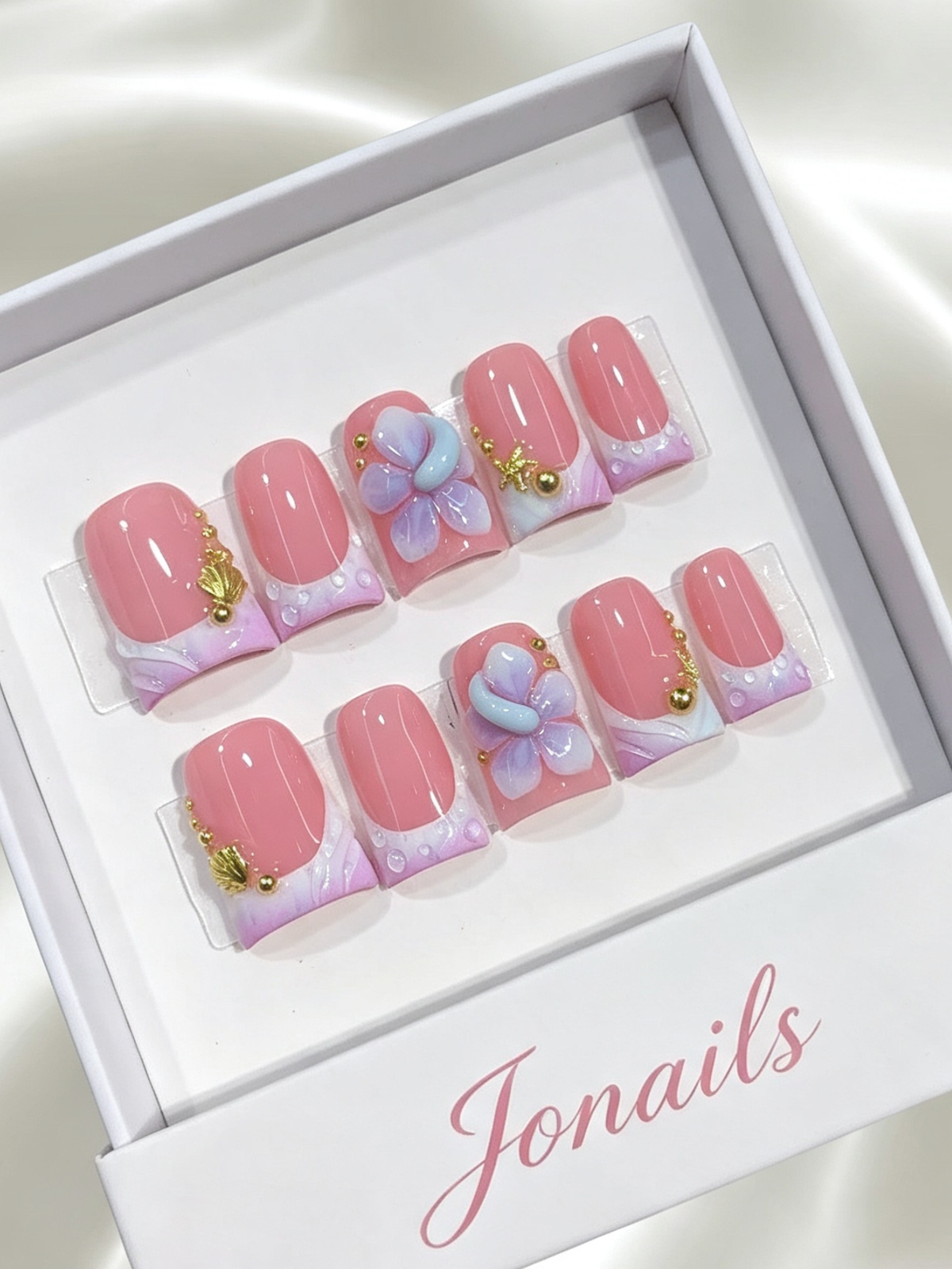Pink press-on nails with lavender French tips, 3D blue purple flower and gold starfish charm
