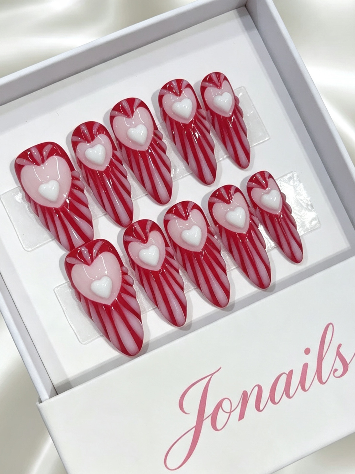 Red and white candy stripe press-on nails with 3D raised heart centerpiece