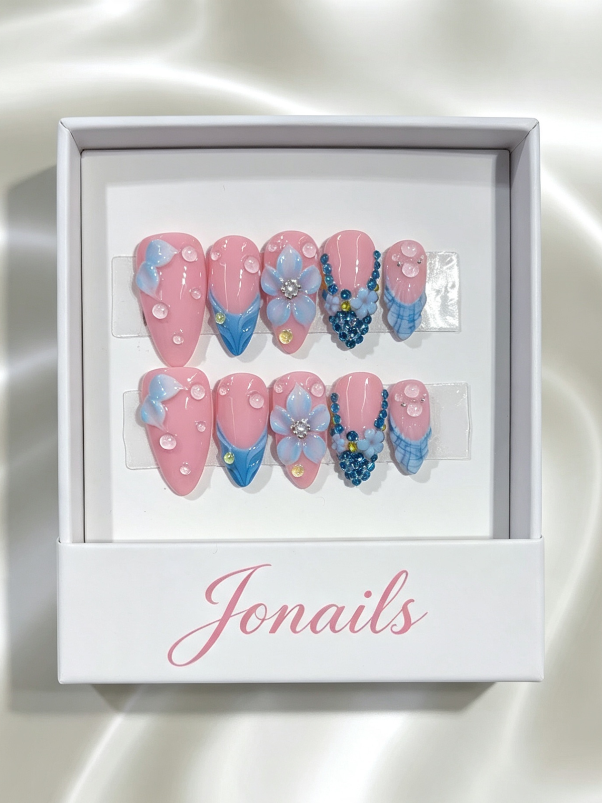 Blush pink press-on nails with 3D blue flowers, teal rhinestone clusters and water droplet details
